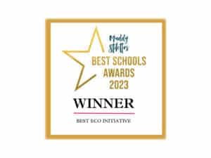 A golden-framed certificate with a star icon states "Muddy Stilettos Best Schools Awards 2023." Below, in bold black text, it reads "WINNER," and underneath, in smaller text, "Best Eco Initiative." TDM wins gold!